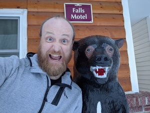 Me next to a wooden statue of a bear making the same rawry face as the bear